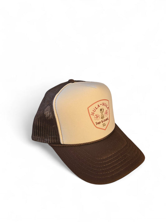 Side view laydown of a foam high profile trucker hat. Graphic is printed with Time to Coast Hula Hula girl. Hat color is beige and brown with a brown mesh back.