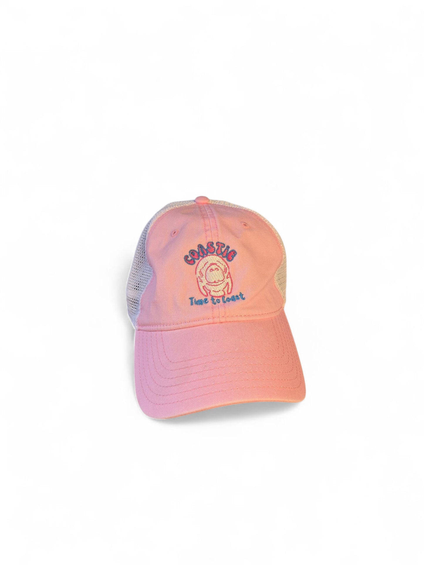 Laydown of the Coastie Manatee embroidered twill low profile trucker hat. Color of hat is washed pink twill with a white embroidered manatee and tan mesh back.
