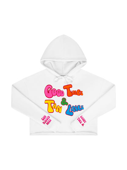 Laydown of a Florida Fleece White Cropped Hoodie Graphic Top.  Graphic is the Time to Coast Good Times & Tan Lines Slogan.  Graphic is in multi colorful words.  Sleeves have hot pink words of sandy toes & sun kissed nose. 