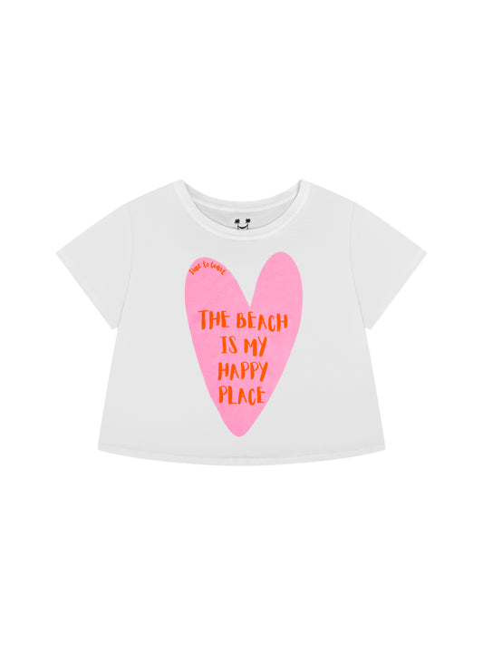 Laydown of a white Time to Coast Palm Cloth crop tee. Graphic is a heart with beach is my happy place slogan. Heart color is pink with red wording. 
