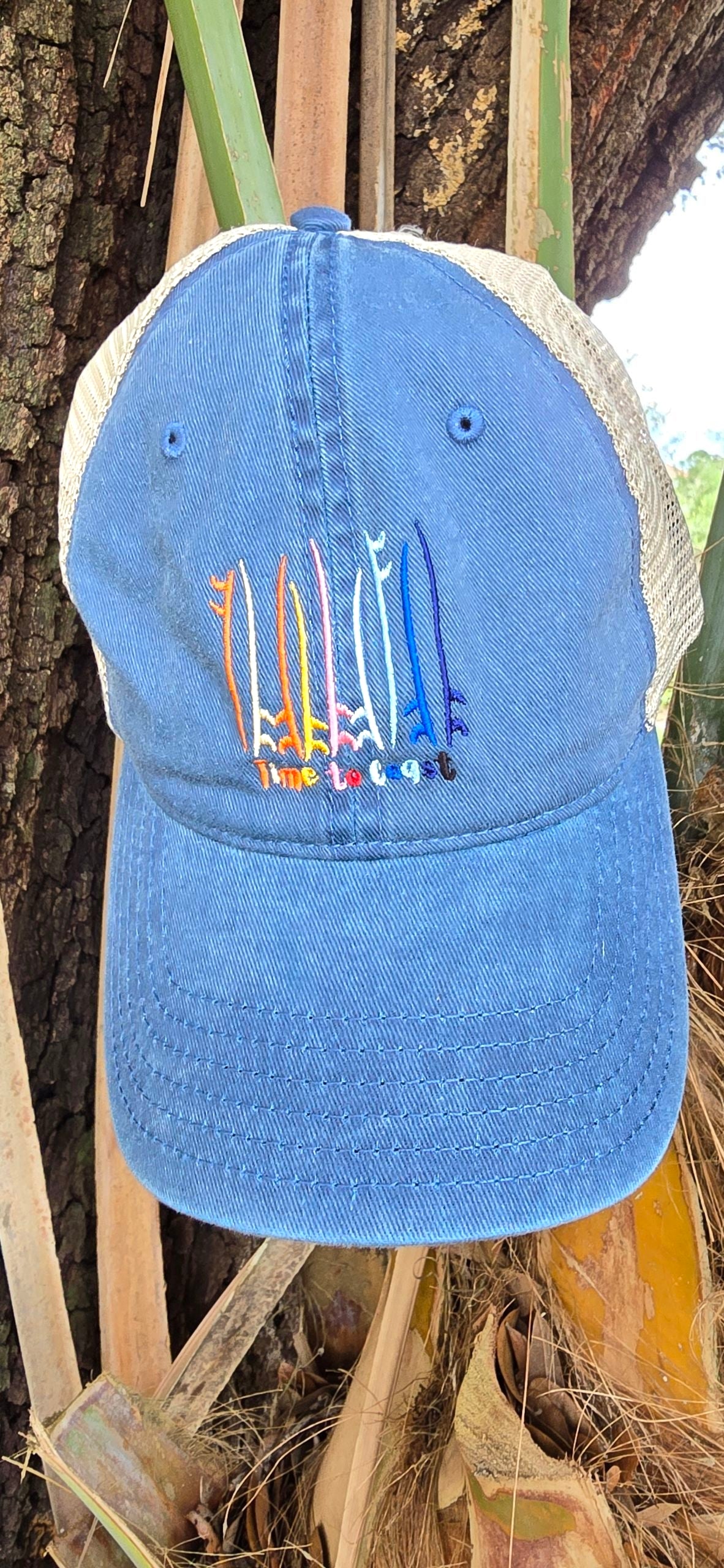 Laydown of the Board Meeting embroidered Time to Coast washed twill navy low profile trucker hat with tan mesh back. Embroidered graphic is of surf and sup boards in multi color.