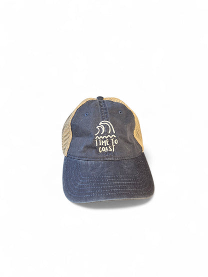 Laydown of the Time to swell low profile trucker washed navy twill hat with tan mesh back. Graphic is an embroidery of surf swell and waves with time to coast in white.