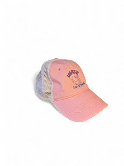 Side laydown of the Coastie Manatee embroidered twill low profile trucker hat. Color of hat is washed pink twill with a white embroidered manatee and tan mesh back.