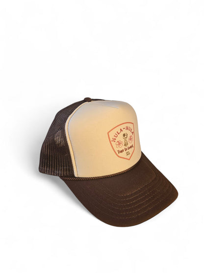 Side view laydown of a foam high profile trucker hat.  Graphic is printed with Time to Coast Hula Hula girl. Hat color is beige and brown with a brown mesh back.