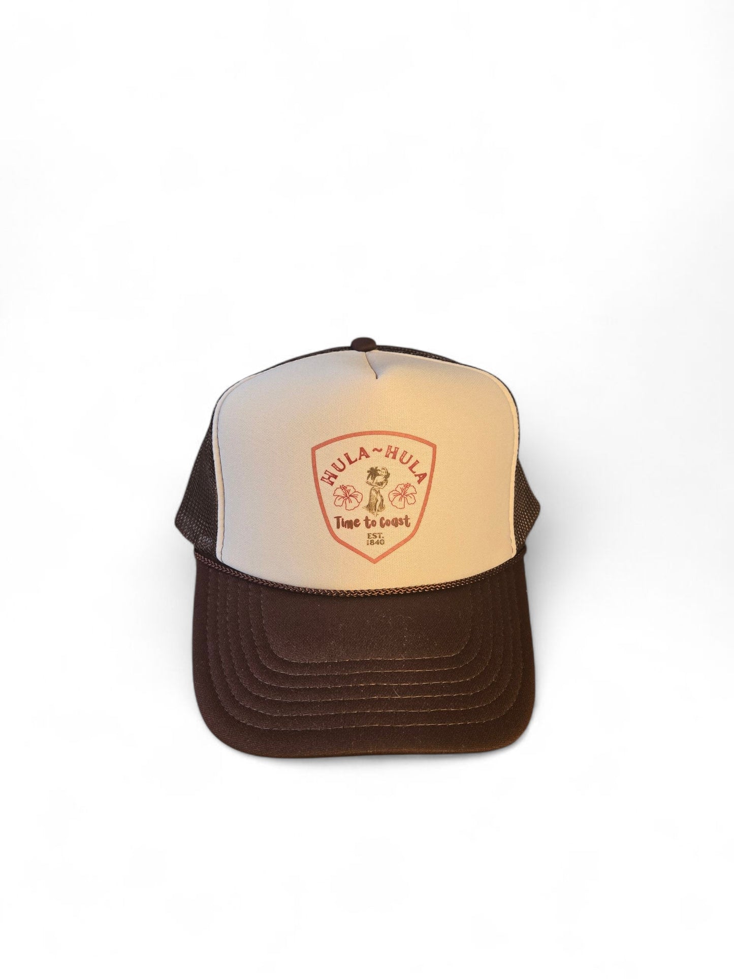 Laydown of a foam high profile trucker hat.  Graphic is printed with Time to Coast Hula Hula girl. Hat color is beige and brown with a brown mesh back.