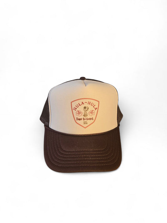 Laydown of a foam high profile trucker hat.  Graphic is printed with Time to Coast Hula Hula girl. Hat color is beige and brown with a brown mesh back.