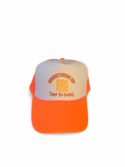 laydown of a foam high profile trucker hat.  Graphic is printed with Time to Coast Sunnyside Up Sun. Hat color is bright orange bill and mesh back with white front. 