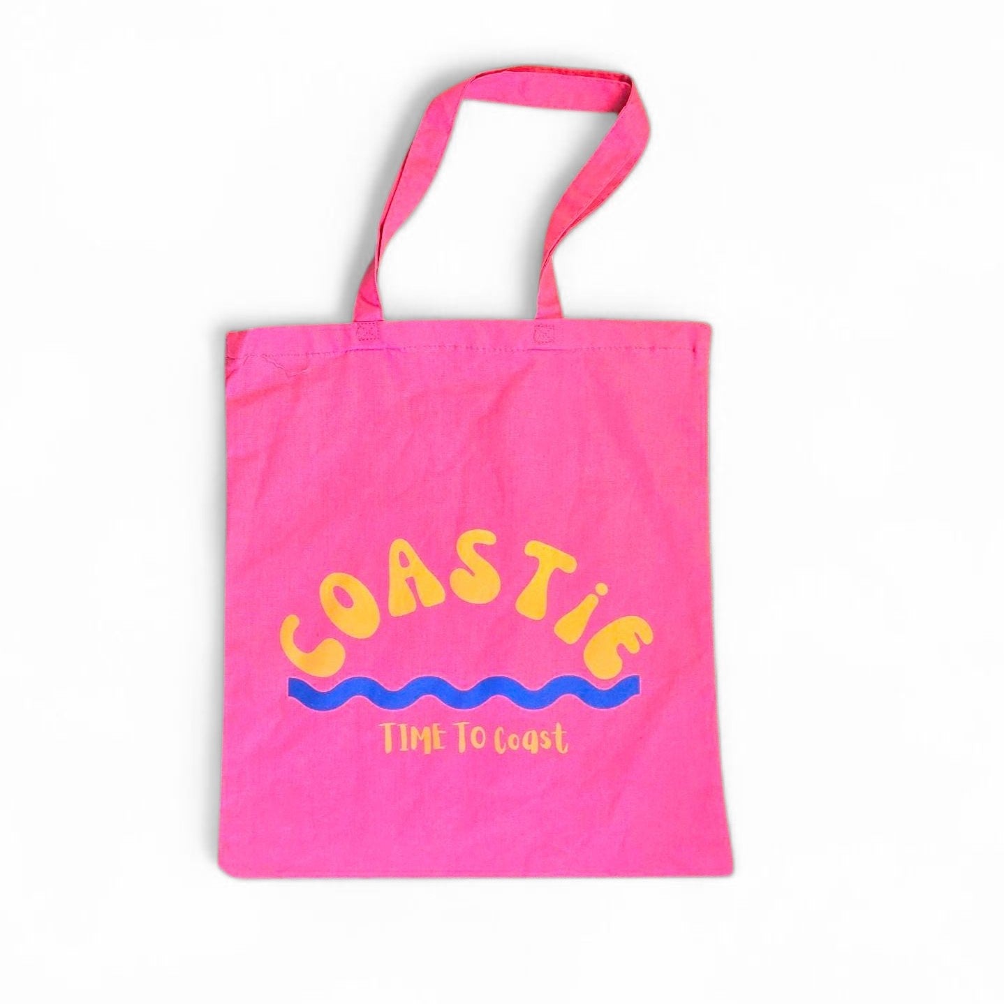 laydown of a hot pink Market Bag.  Bag has a Coastie word graphic, wave and time to coast logo