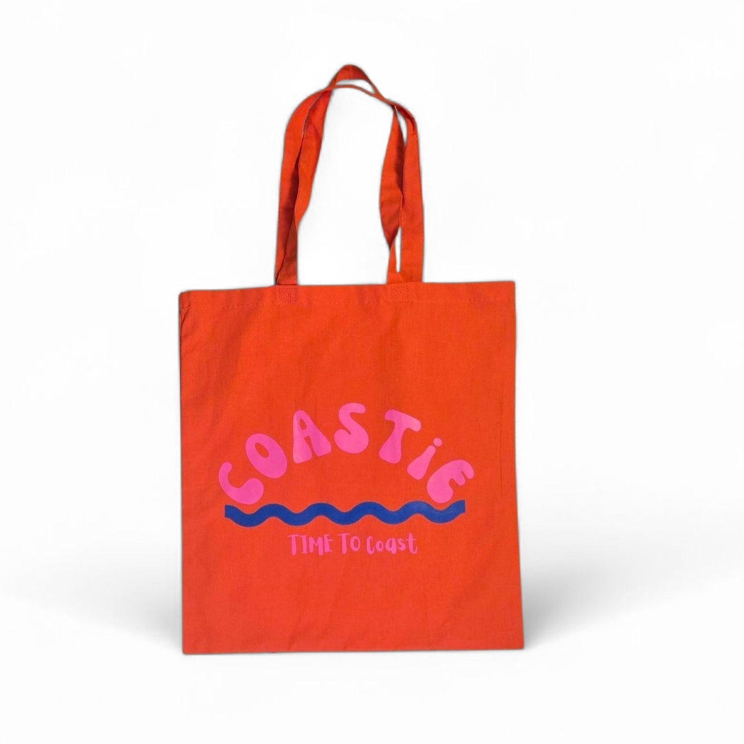 laydown of a orange Market Bag.  Bag has a Coastie word graphic, wave and time to coast logo