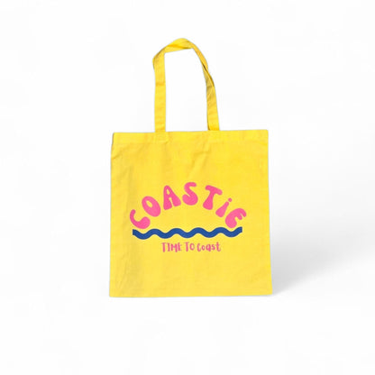 laydown of a yellow Market Bag.  Bag has a Coastie word graphic, wave and time to coast logo
